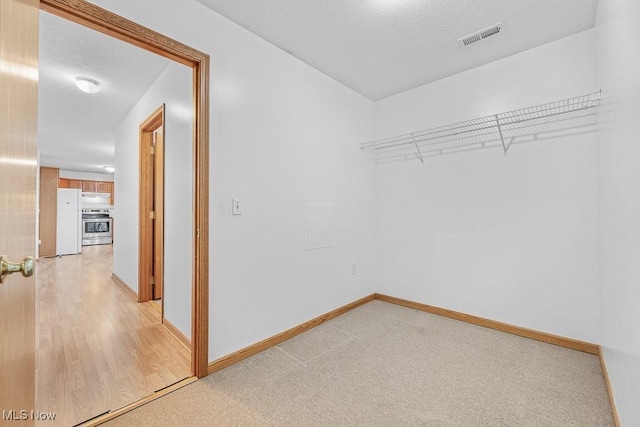 spacious closet featuring visible vents and light colored carpet