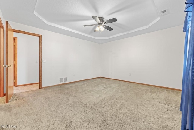 spare room featuring a tray ceiling, carpet, and visible vents