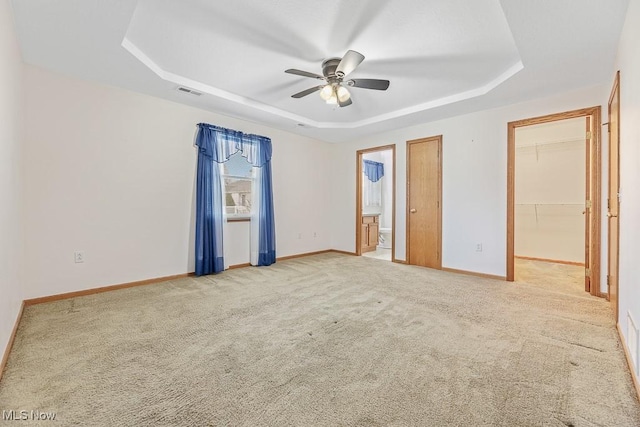 unfurnished bedroom with carpet floors, visible vents, baseboards, and a raised ceiling