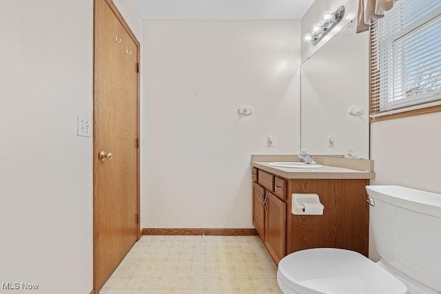 half bathroom with baseboards, vanity, toilet, and tile patterned floors