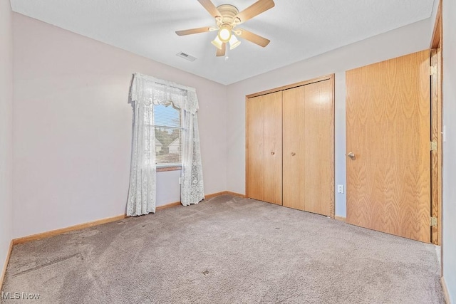 unfurnished bedroom with carpet, a closet, visible vents, a ceiling fan, and baseboards