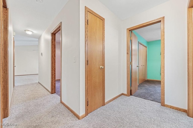 hallway with carpet flooring and baseboards