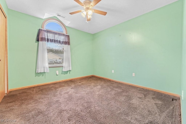 carpeted spare room with baseboards, visible vents, and ceiling fan