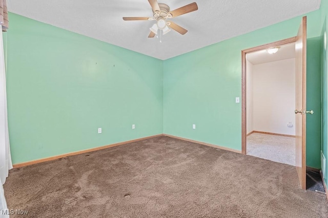 carpeted empty room featuring ceiling fan and baseboards