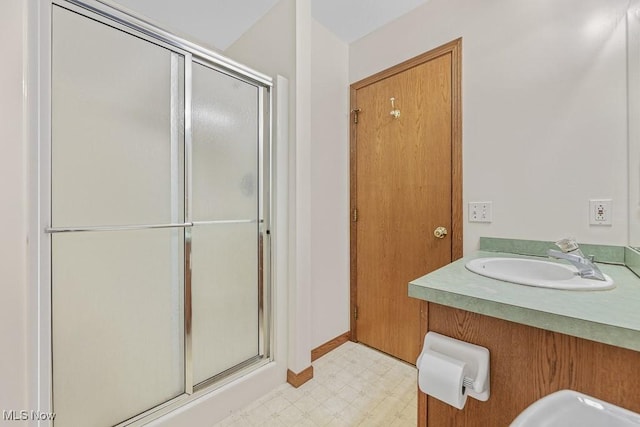 bathroom with a shower stall, baseboards, a sink, and tile patterned floors