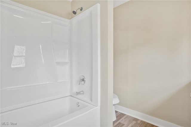 full bath featuring toilet, baseboards, shower / washtub combination, and wood finished floors