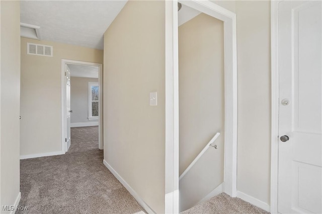 corridor with baseboards, visible vents, carpet flooring, and an upstairs landing