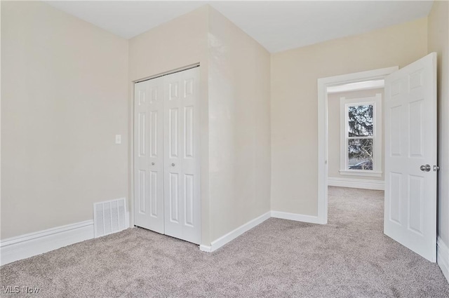 unfurnished bedroom with carpet floors, a closet, visible vents, and baseboards