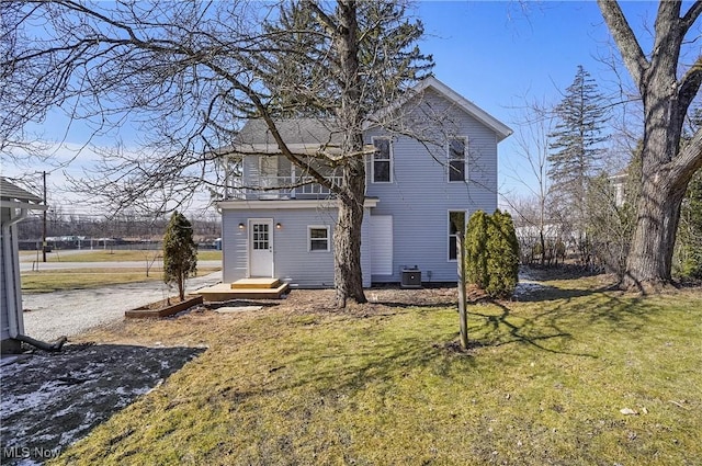 back of house featuring driveway, a lawn, and central air condition unit