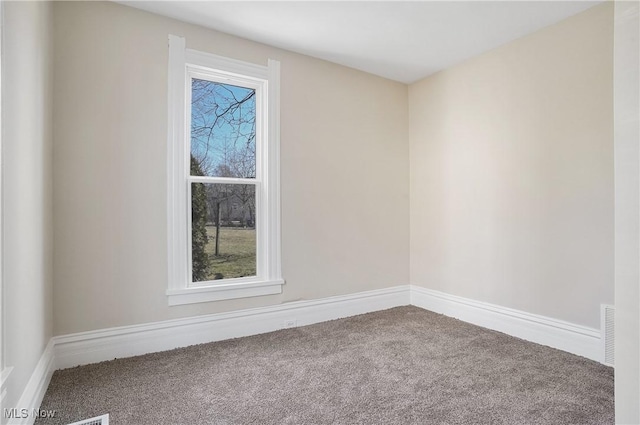 spare room featuring carpet and baseboards