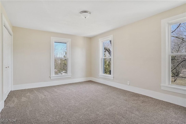 empty room featuring a healthy amount of sunlight, carpet flooring, and baseboards