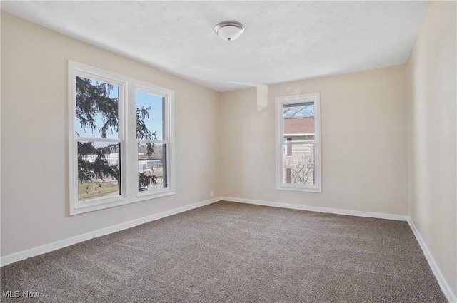 carpeted spare room with a textured ceiling and baseboards