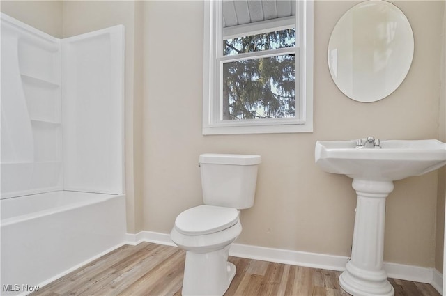 full bathroom with toilet, baseboards,  shower combination, and wood finished floors