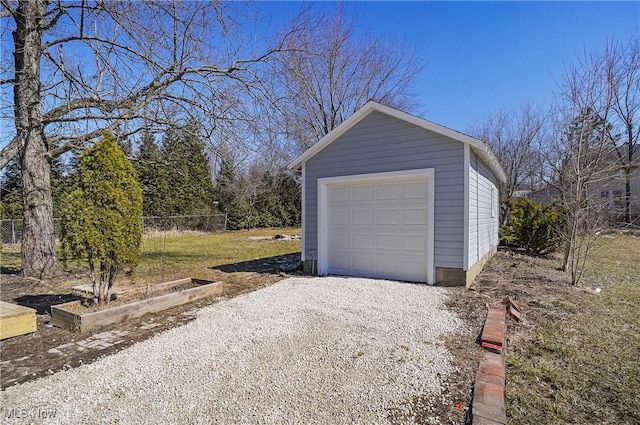 detached garage with gravel driveway and fence