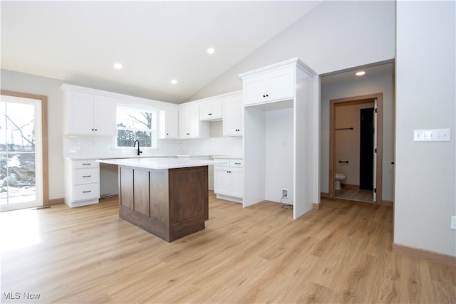 kitchen with light wood finished floors, a kitchen island, and white cabinetry