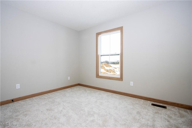 carpeted spare room featuring visible vents and baseboards