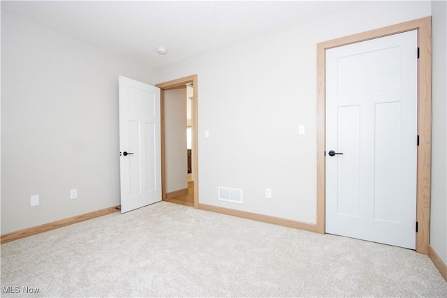 unfurnished bedroom featuring light carpet, visible vents, and baseboards