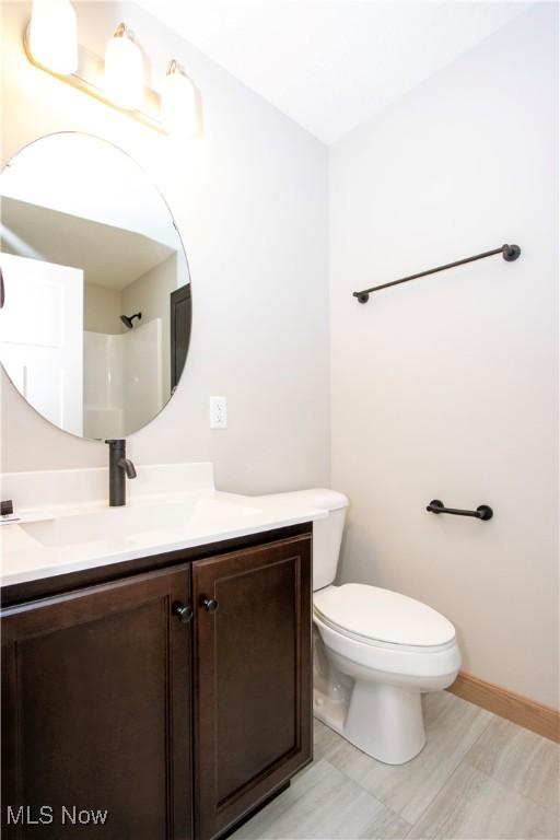 bathroom featuring toilet, baseboards, and vanity