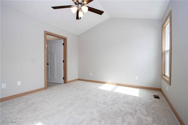 empty room featuring lofted ceiling, ceiling fan, light colored carpet, visible vents, and baseboards