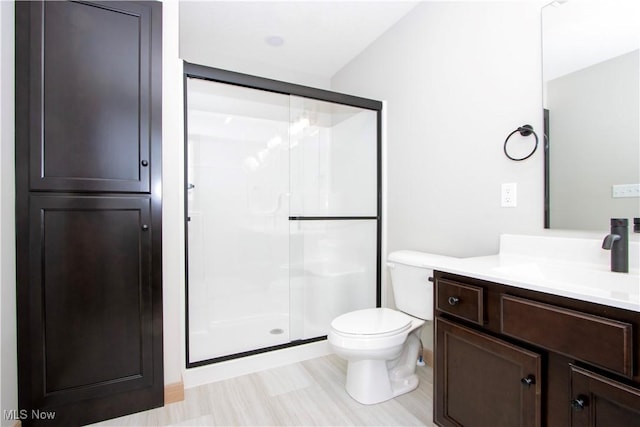 full bath with a stall shower, vanity, and toilet