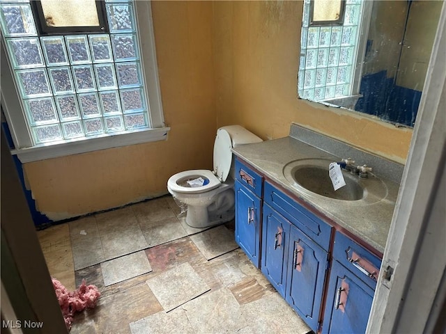 bathroom with stone finish floor, vanity, and toilet