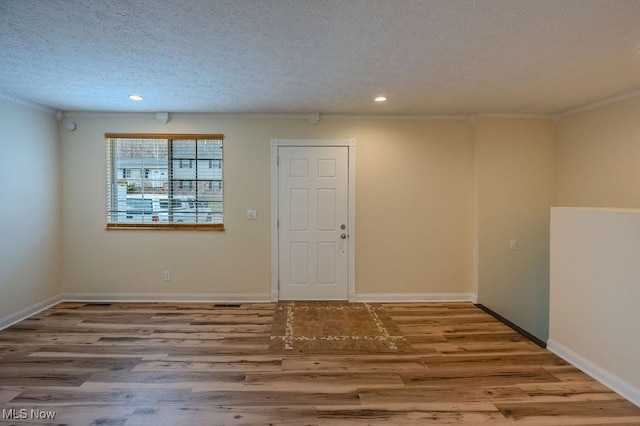 empty room featuring a textured ceiling, wood finished floors, and baseboards