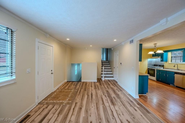 unfurnished living room with light wood-style floors, stairs, baseboards, and a textured ceiling