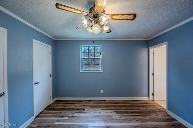 spare room with a textured ceiling, ornamental molding, and wood finished floors