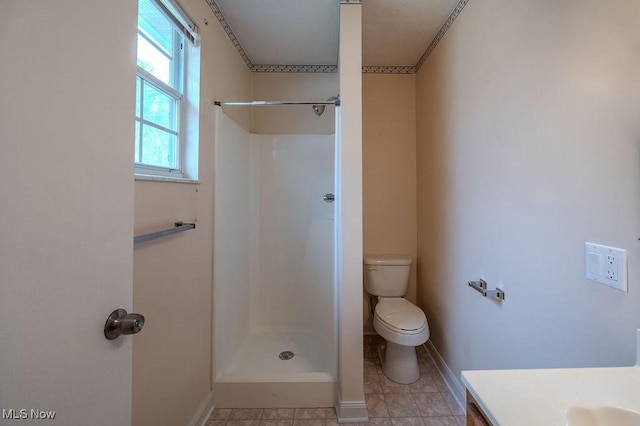 full bath featuring a shower, vanity, toilet, and baseboards