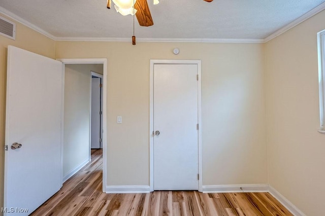 unfurnished bedroom with ornamental molding, visible vents, light wood-style flooring, and baseboards