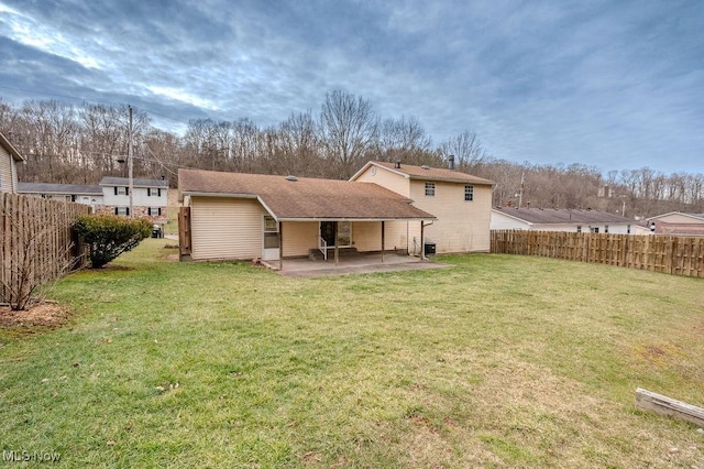 rear view of property featuring a patio, a yard, and a fenced backyard