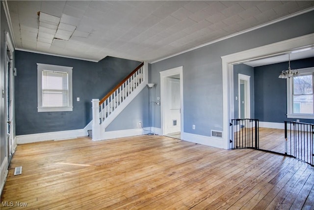 empty room with hardwood / wood-style flooring, visible vents, baseboards, and an inviting chandelier