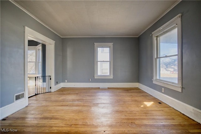 unfurnished room featuring light wood-style flooring, visible vents, baseboards, and ornamental molding