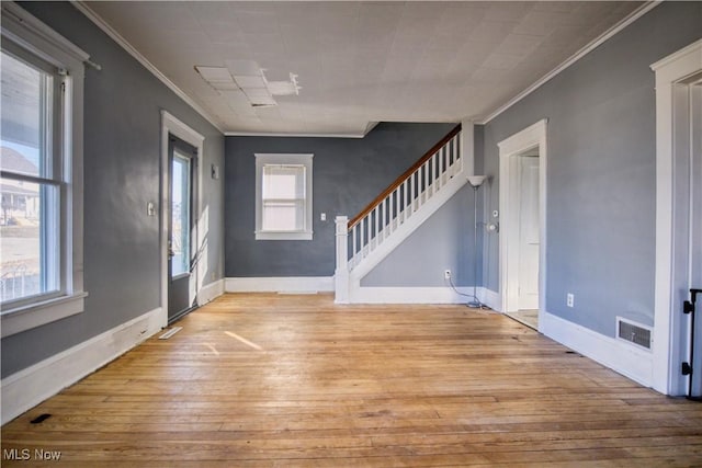 foyer with baseboards, crown molding, light wood finished floors, and stairs