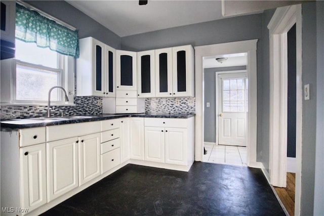 kitchen featuring dark countertops, tasteful backsplash, and a sink