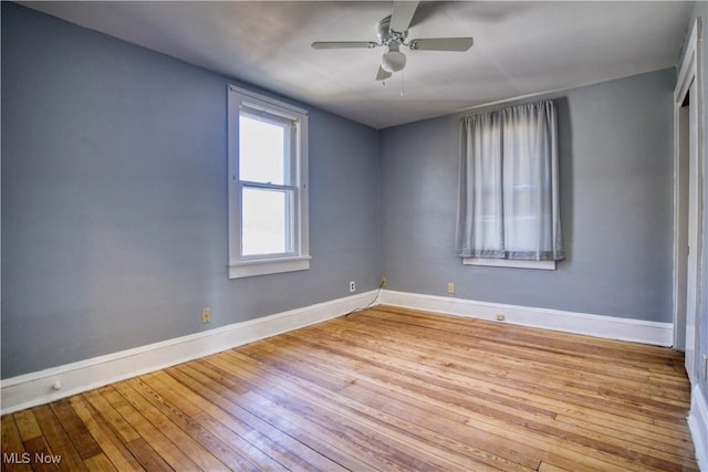 spare room with wood-type flooring, a ceiling fan, and baseboards