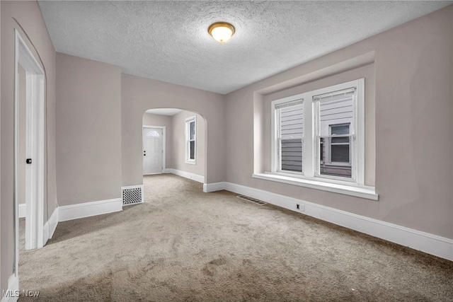 unfurnished room featuring baseboards, visible vents, arched walkways, and carpet flooring