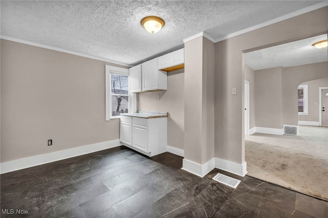 kitchen with visible vents, arched walkways, baseboards, ornamental molding, and white cabinetry