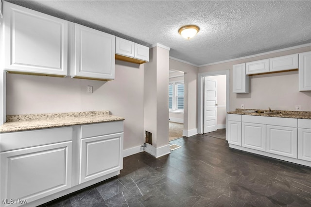 kitchen featuring light stone counters, white cabinetry, a sink, and baseboards