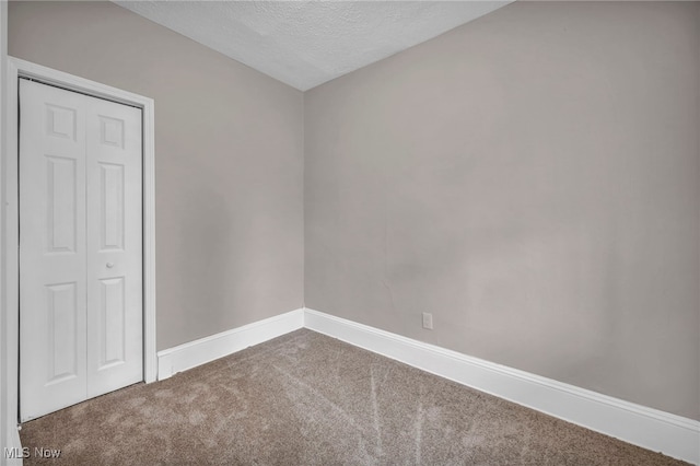 empty room featuring carpet, a textured ceiling, and baseboards