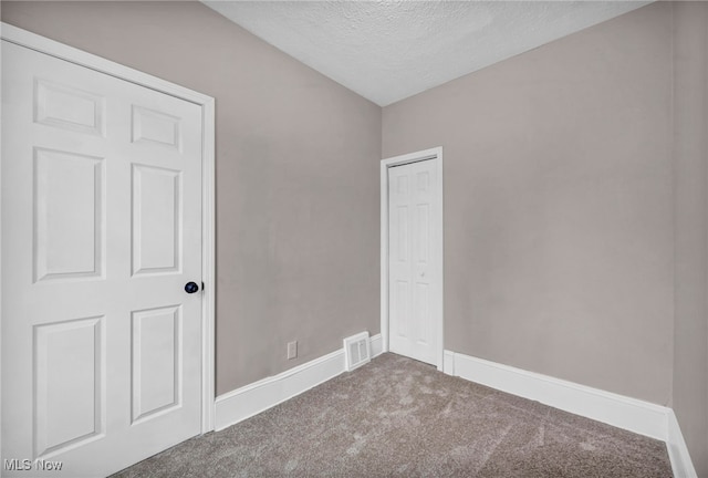 carpeted spare room with a textured ceiling, visible vents, and baseboards