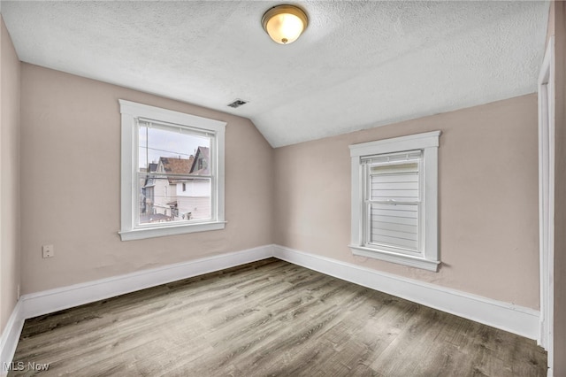 bonus room with visible vents, baseboards, wood finished floors, vaulted ceiling, and a textured ceiling