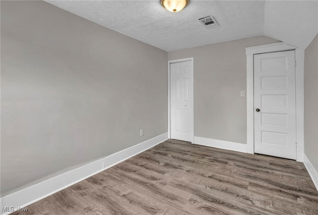 unfurnished bedroom featuring a closet, a textured ceiling, baseboards, and wood finished floors