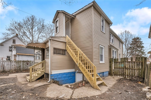 back of property with entry steps and fence