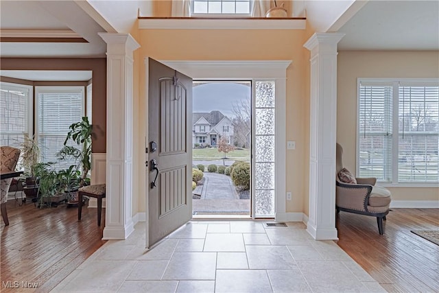 entryway with ornate columns, baseboards, and light wood finished floors