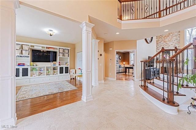 foyer entrance with baseboards, stairway, wood finished floors, a high ceiling, and ornate columns