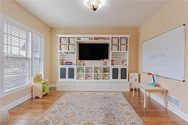 game room featuring baseboards, visible vents, and wood finished floors