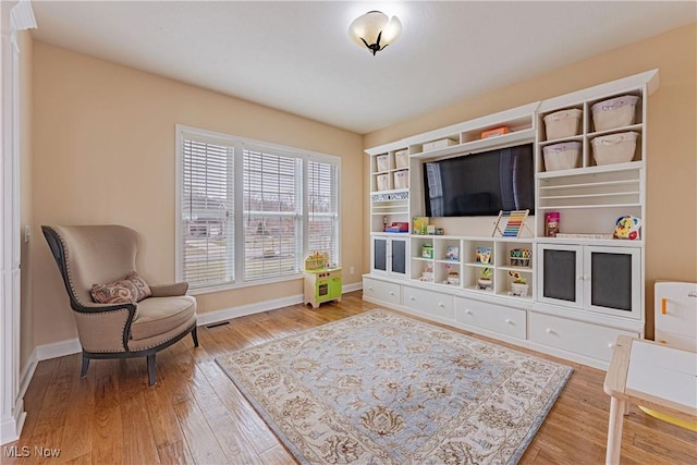 sitting room with wood finished floors, visible vents, and baseboards