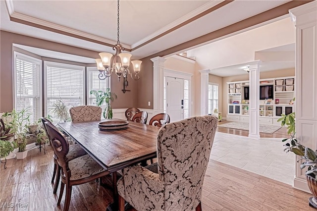 dining area featuring a wealth of natural light, a tray ceiling, and ornate columns