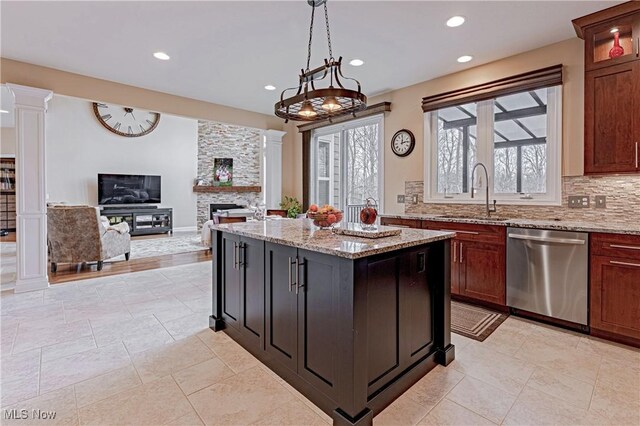 kitchen with decorative columns, decorative backsplash, stainless steel dishwasher, a fireplace, and a sink